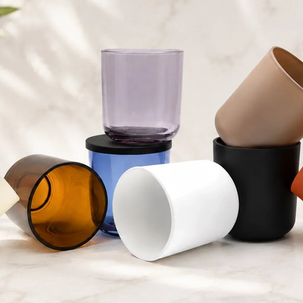 Assortment of candle-making containers and vessels in various shapes, sizes, and colors arranged on a light surface, showcasing options for candles and home fragrance products.