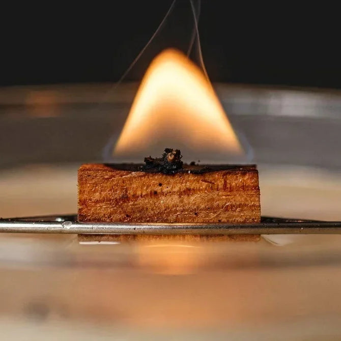 Close-up of a wooden candle wick burning in melted wax